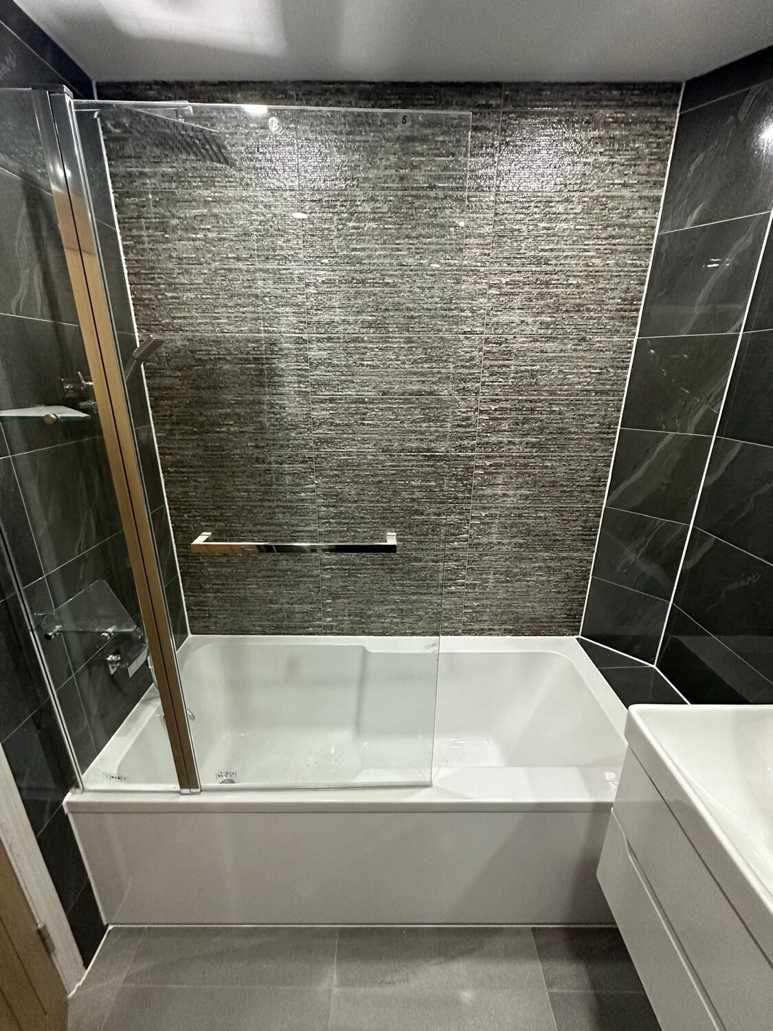 Bath with dark textured feature wall and chrome fittings