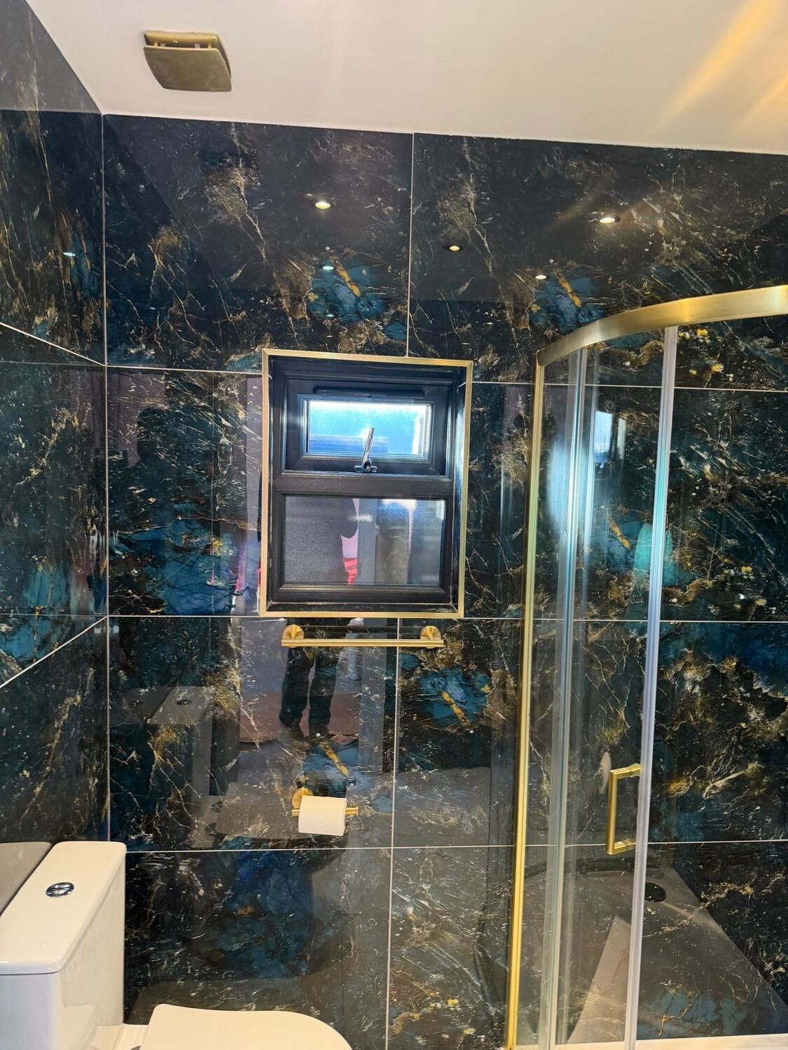 Shower enclosure with blue and gold marble-effect tiles